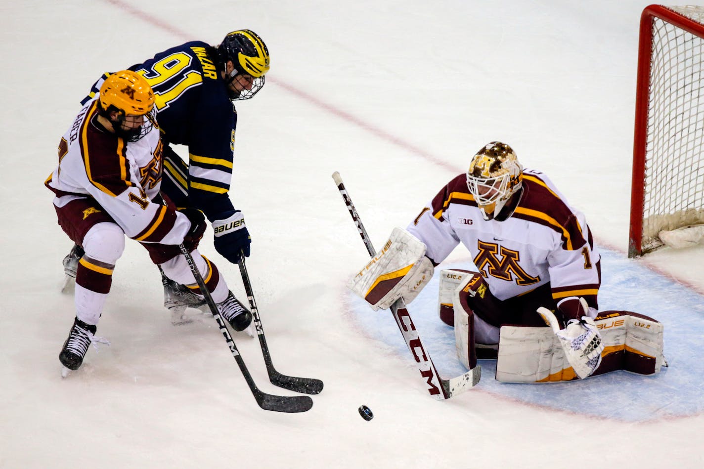 Minnesota goaltender Justen Close (1) blocks a shot by Michigan forward Frank Nazar III (91) with defense from Minnesota defenseman Brock Faber (14) in the second period of an NCAA hockey game, Saturday, March 18, 2023 in Minneapolis. (AP Photo/Andy Clayton-King)