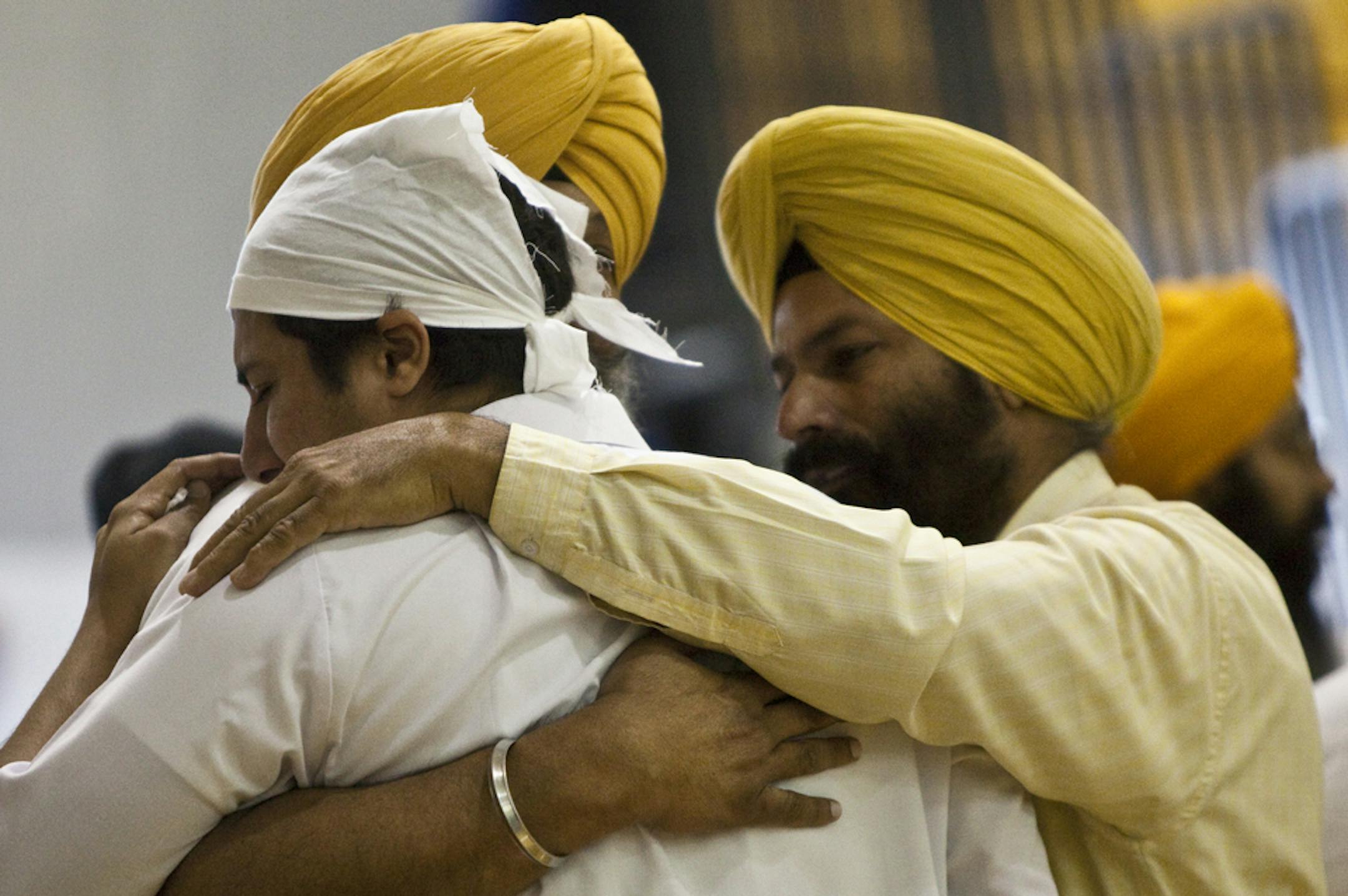 Mourners embrace during wake and visitation services for the six victims of the Sikh temple shooting at the Oak Creek High School gymnasium in Oak Creek, Wis., Aug. 10, 2012.