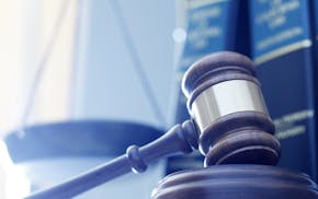 iStock A gavel rests on its sounding block with a several law books and a justice scale out of focus in the background.