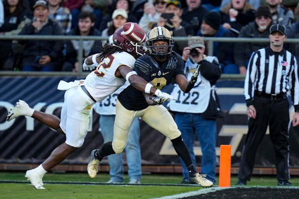 Purdue wide receiver TJ Sheffield, right, makes a catch for a touchdown as he's hit by Minnesota defensive back Darius Green (12) during the first hal