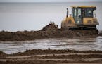 A bulldozer pushed dirt along Park Point beach on Tuesday as part of an effort to raise the beach front and protect homes along the island.