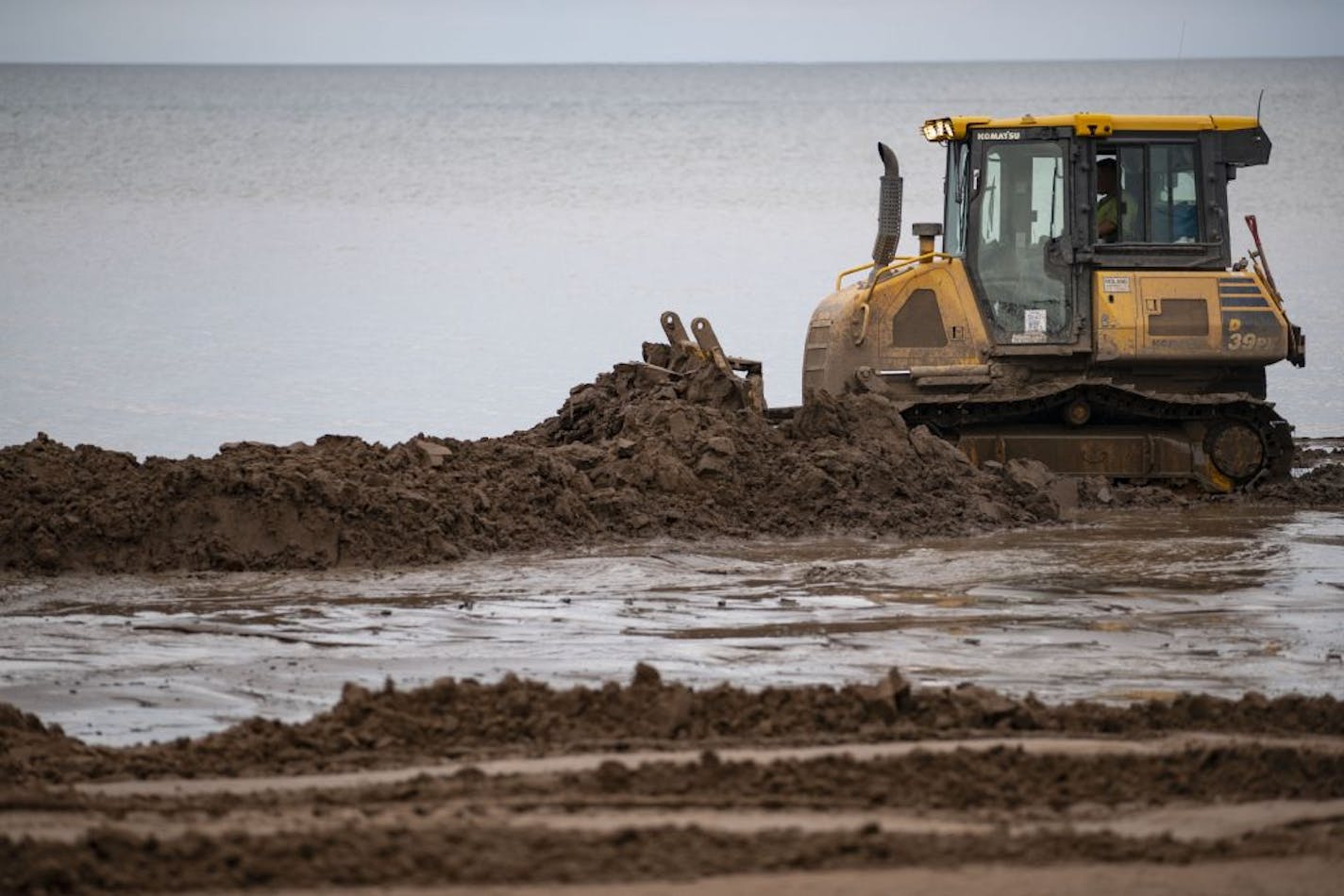 A bulldozer pushed dirt along Park Point beach on Tuesday as part of an effort to raise the beach front and protect homes along the island.