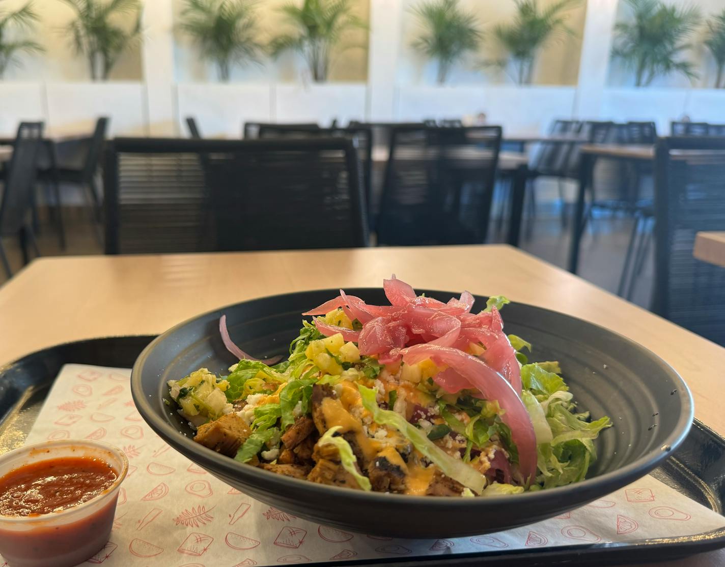 An achiote chicken rice bowl at Puralima loaded with black beans, pickled red onions, chipotle cashew cream and pineapple pico.