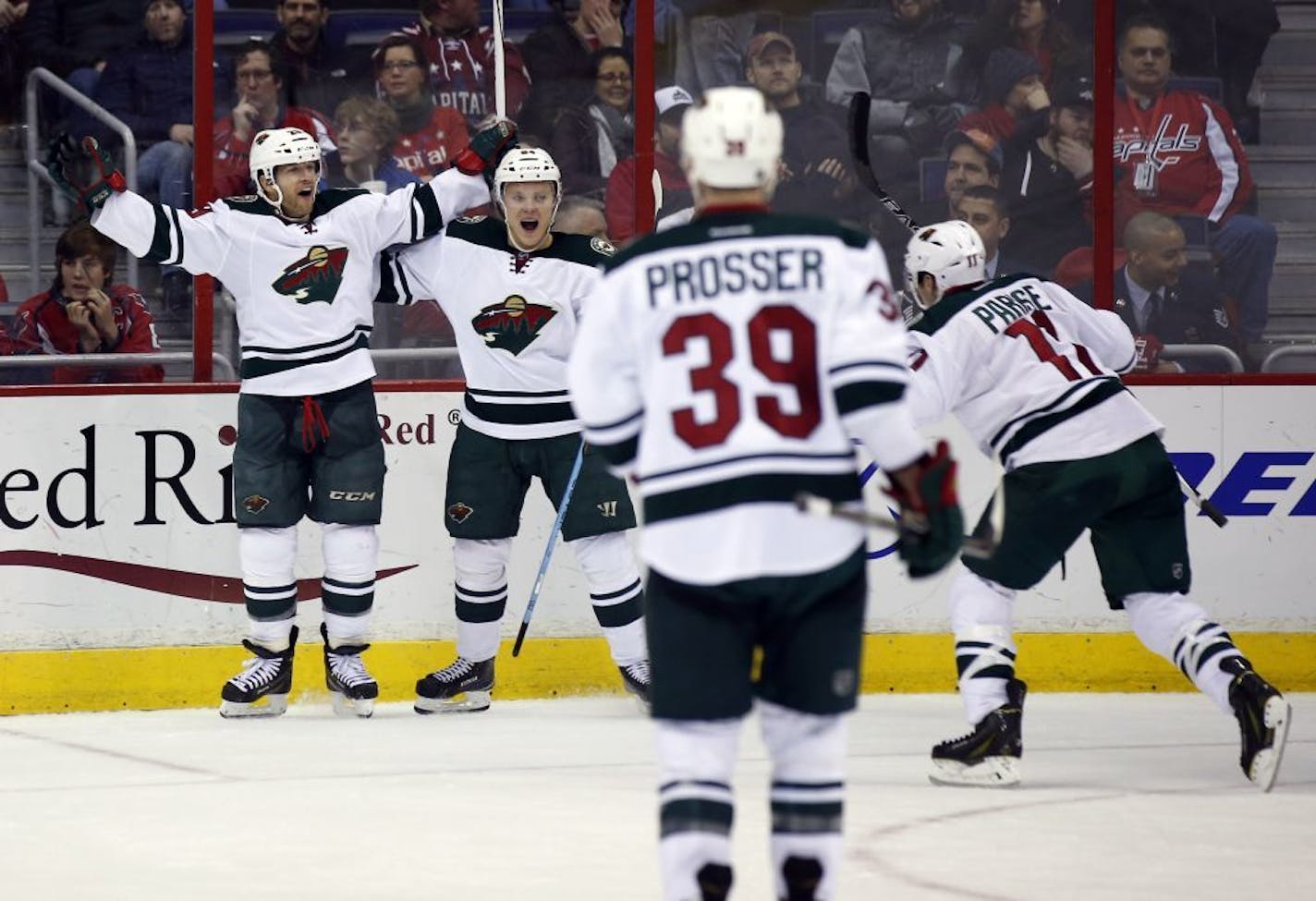 Minnesota Wild right wing Jason Pominville, left, celebrates his goal with center Mikael Granlund (64), from Finland, as defenseman Nate Prosser (39) and left wing Zach Parise (11) come to join, during the third period of an NHL hockey game against the Washington Capitals, Thursday, March 5, 2015, in Washington. The Wild won 2-1.