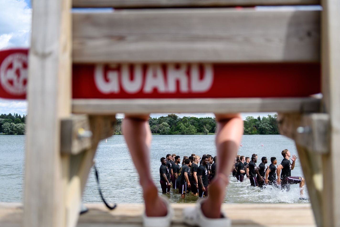 A lifeguard watched as Gophers football players ran through the shallows of Lake Nokomis in 2017.