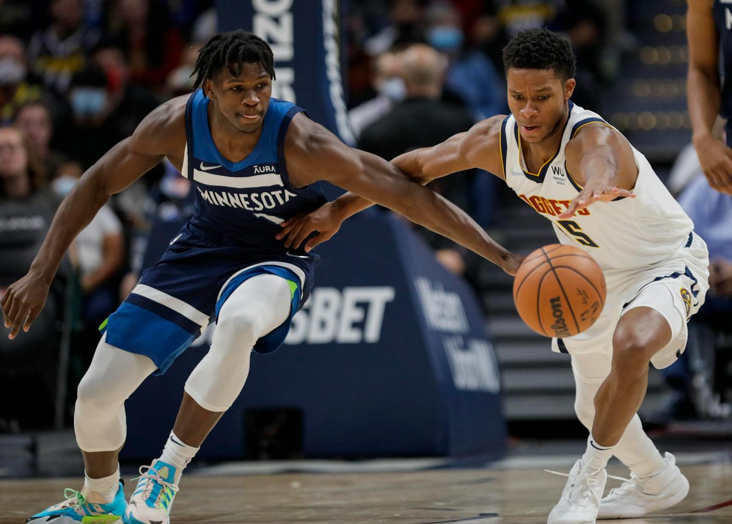 Minnesota Timberwolves forward Anthony Edwards, left, and Denver Nuggets guard PJ Dozier reach for the ball in the first quarter of a preseason NBA basketball game in Denver, Friday, Oct. 8, 2021. (AP Photo/Joe Mahoney)