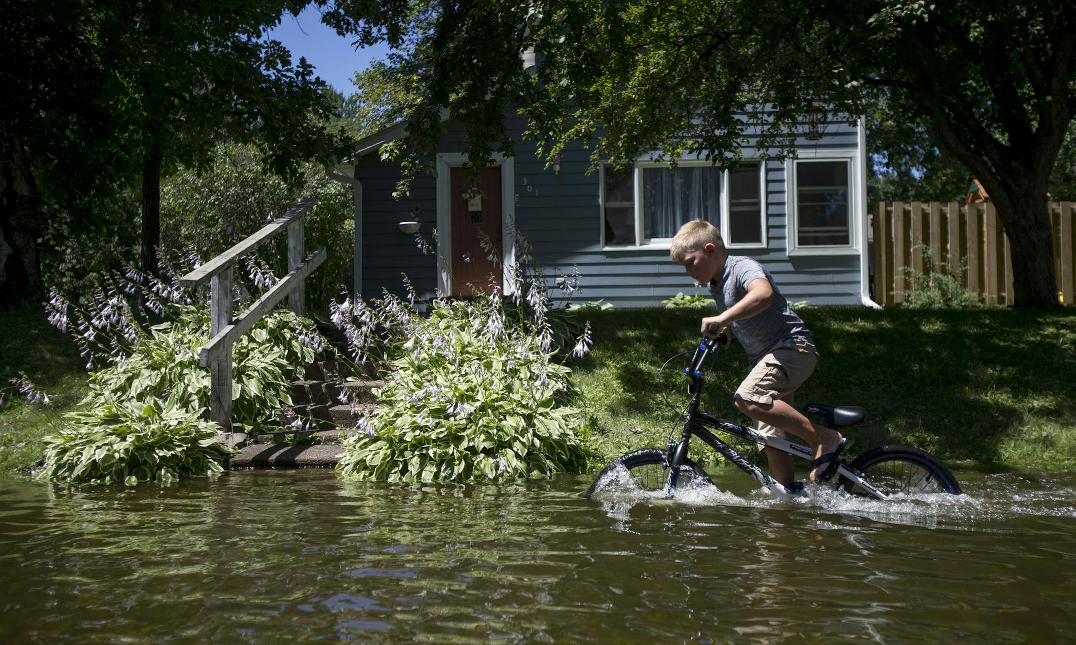 Anders Fix tries to ride his bike through the water to get to the other side the street. ] ALEX KORMANN • alex.kormann@startribune.com Mora, MN is a small rural community in central Minnesota. On Thursday 8-10 inches of rain fell in a matter of hours causing flash flooding throughout the area. But as the water drained from all over the town it caused Lake Mora and Snake River to rise rapidly and flood local streets, highways and county roads. On Monday N. Wood street was still underwater