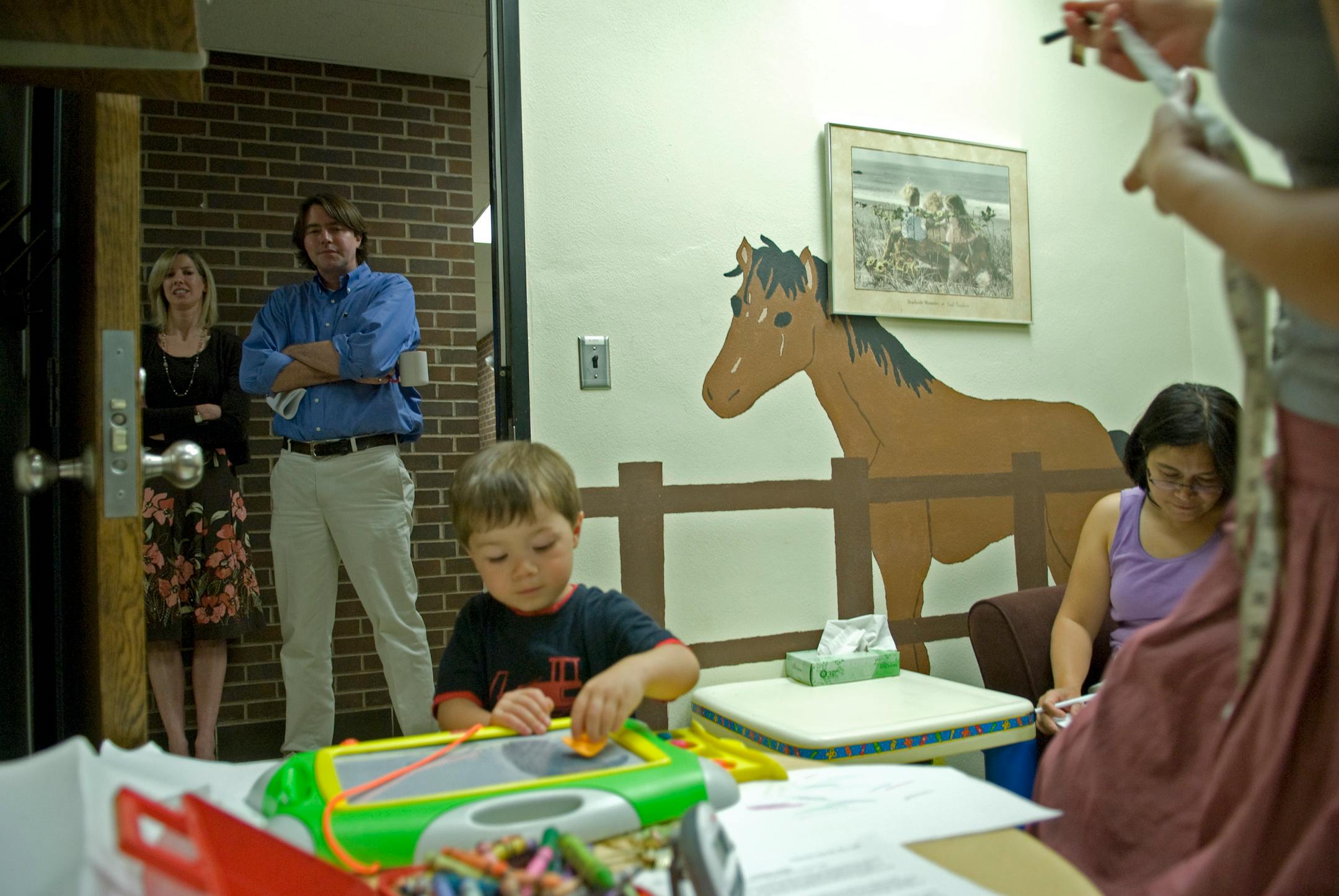 Dr. Phil Zelazo, who is leading the University of Minnesota's research, watches from the hallway as Aidan Oakmand is prepared for the day's experiment.