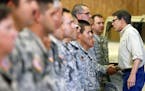 FILE - In this Aug. 13, 2014 file phone, Gov. Rick Perry shakes hands with National Guard troops training at Camp Swift in Bastrop, Texa. President Do