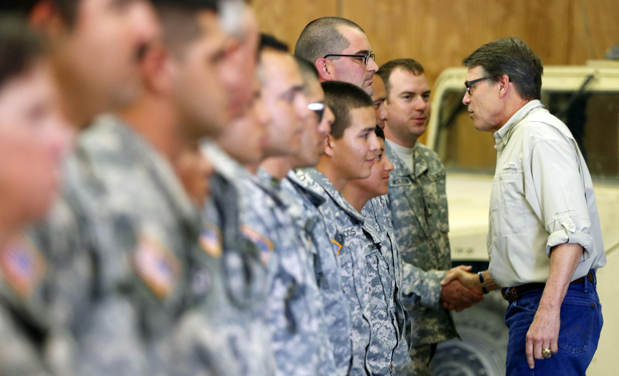 FILE - In this Aug. 13, 2014 file phone, Gov. Rick Perry shakes hands with National Guard troops training at Camp Swift in Bastrop, Texa. President Donald Trump's announcement Tuesday, April 3, 2018, that he wants to use the military to secure the U.S.-Mexico border echoes the response of Texas leaders during a surge of Central American children crossing the Rio Grande four years ago. Former Gov. Perry ordered the Texas National Guard to deploy along the Rio Grande in July 2014. (William Luther/