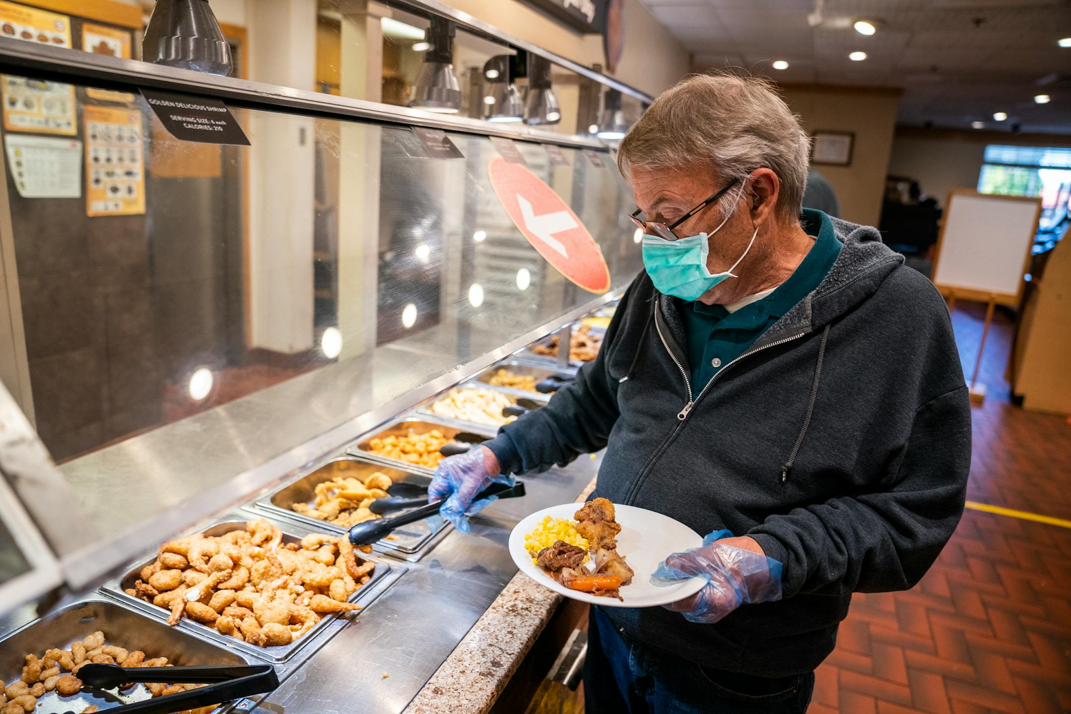 Bob Hemp of Brooklyn Park served himself wearing a mask and gloves at the Golden Coral Buffet and Grill in Maple Grove on Friday.