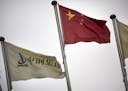 In this Wednesday, Nov. 18, 2015 photo, SinoSteel Corp. and Chinese flags fly outside of the company's headquarters in in Beijing. China's government 