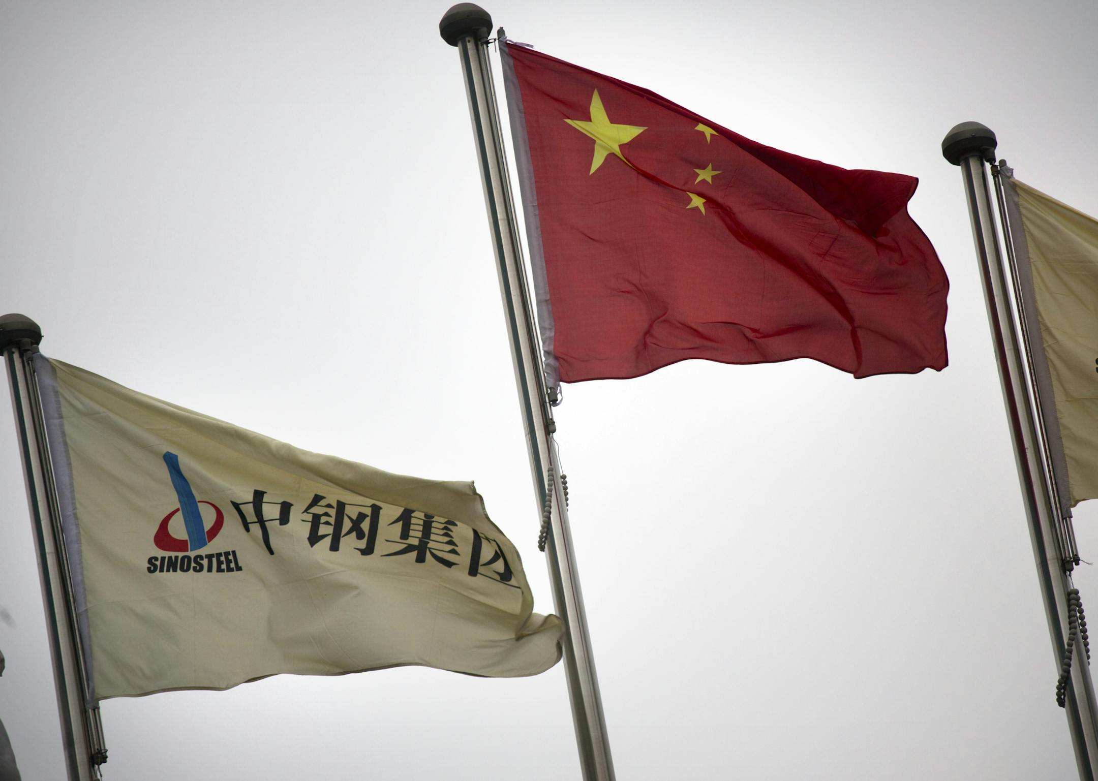 In this Wednesday, Nov. 18, 2015 photo, SinoSteel Corp. and Chinese flags fly outside of the company's headquarters in in Beijing. China's government has allowed a growing number of defaults, hoping investors will be encouraged to look more closely at companies and force risky borrowers to pay more. Now, that stance is being tested by a credit crunch involving SinoSteel Corp., a steel maker that is owned by the Chinese Cabinet and part of an industry the Communist Party says is a pillar of the e
