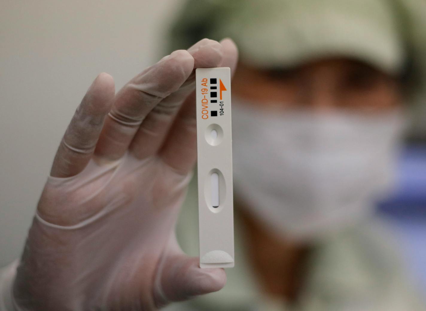 An employee holds up an antibody test cartridge from an ichroma COVID-19 Ab testing kit on a production line in Chuncheon, South Korea, on April 17, 2020.