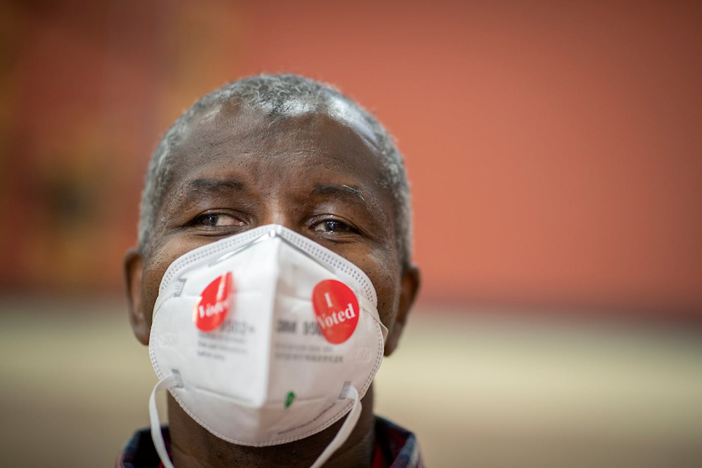 Election volunteer Dwane Martin sported some "I Voted" stickers on his face mask as he handed them out at Jimmy Lee Recreation Center in St. Paul on Aug. 11, 2020.