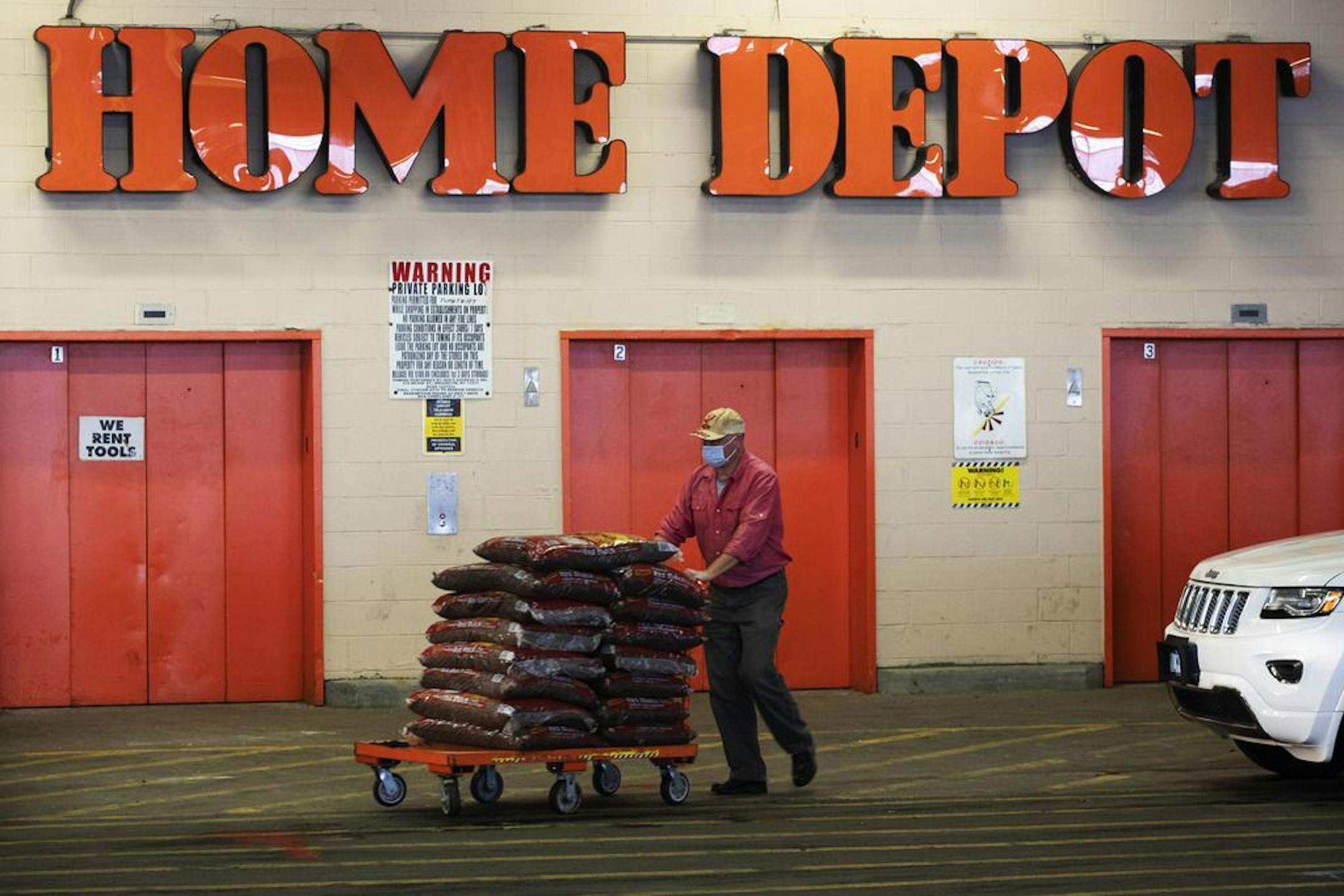FILE - In this April 3, 2020 file photo, a Home Depot customer pushes a cart loaded with supplies in New York. Home Depot is buying HD Supply Co., a distributor of maintenance, repair and operations products in the multifamily and hospitality end markets, in a deal valued at about $8 billion. The transaction is expected to close during Home Depot's fiscal fourth quarter.