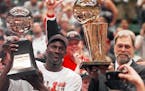FILE--Chicago Bulls' Michael Jordan, left, holds the Most Valuable Player trophy as coach Phil Jackson holds the NBA Championship trophy after the Bul