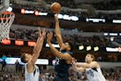 Timberwolves center Karl-Anthony Towns shoots against Mavericks defenders Dwight Powell (7) and Dirk Nowitzki (41)