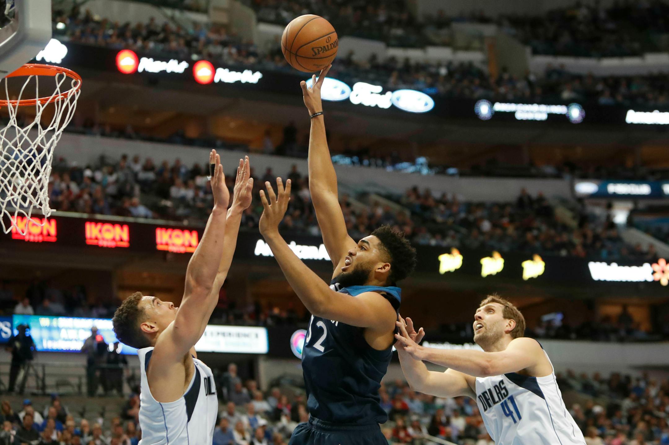 Timberwolves center Karl-Anthony Towns shoots against Mavericks defenders Dwight Powell (7) and Dirk Nowitzki (41)