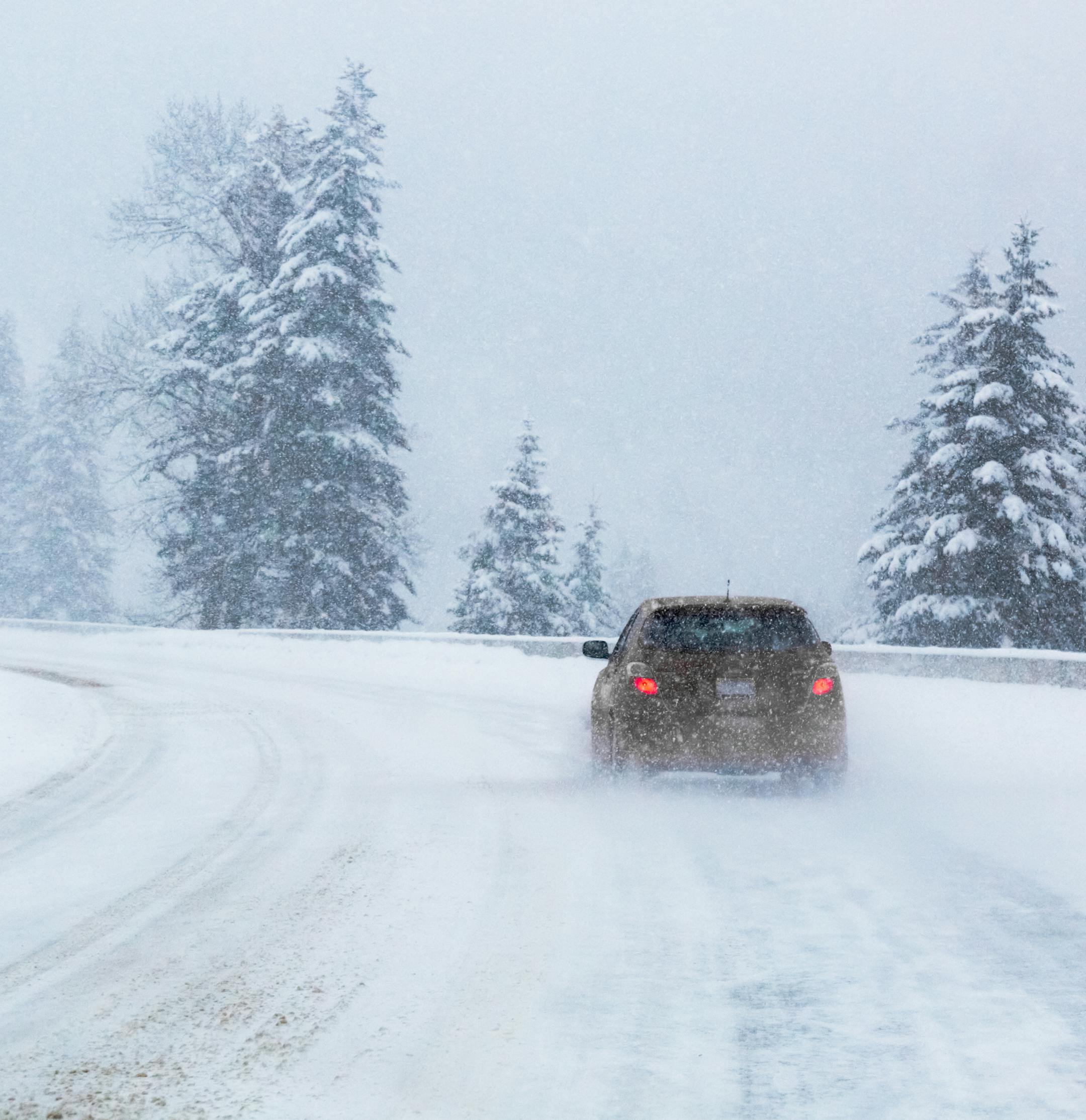 Car traveling on icy curve on I-90 freeway over Lookout Pass in Montana. Mountain snow storm and foggy conditions.