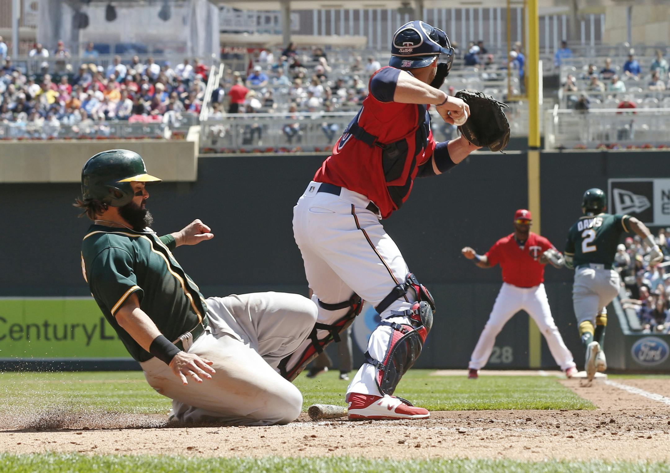 Oakland Athletics' Jeff Decker, left, slides toward the plate but is forced out by Minnesota Twins catcher Chris Gimenez on a bases-loaded fielder's choice hit into by Khris Davis, right background, in the fourth inning of a baseball game Thursday, May 4, 2017, in Minneapolis. (AP Photo/Jim Mone)