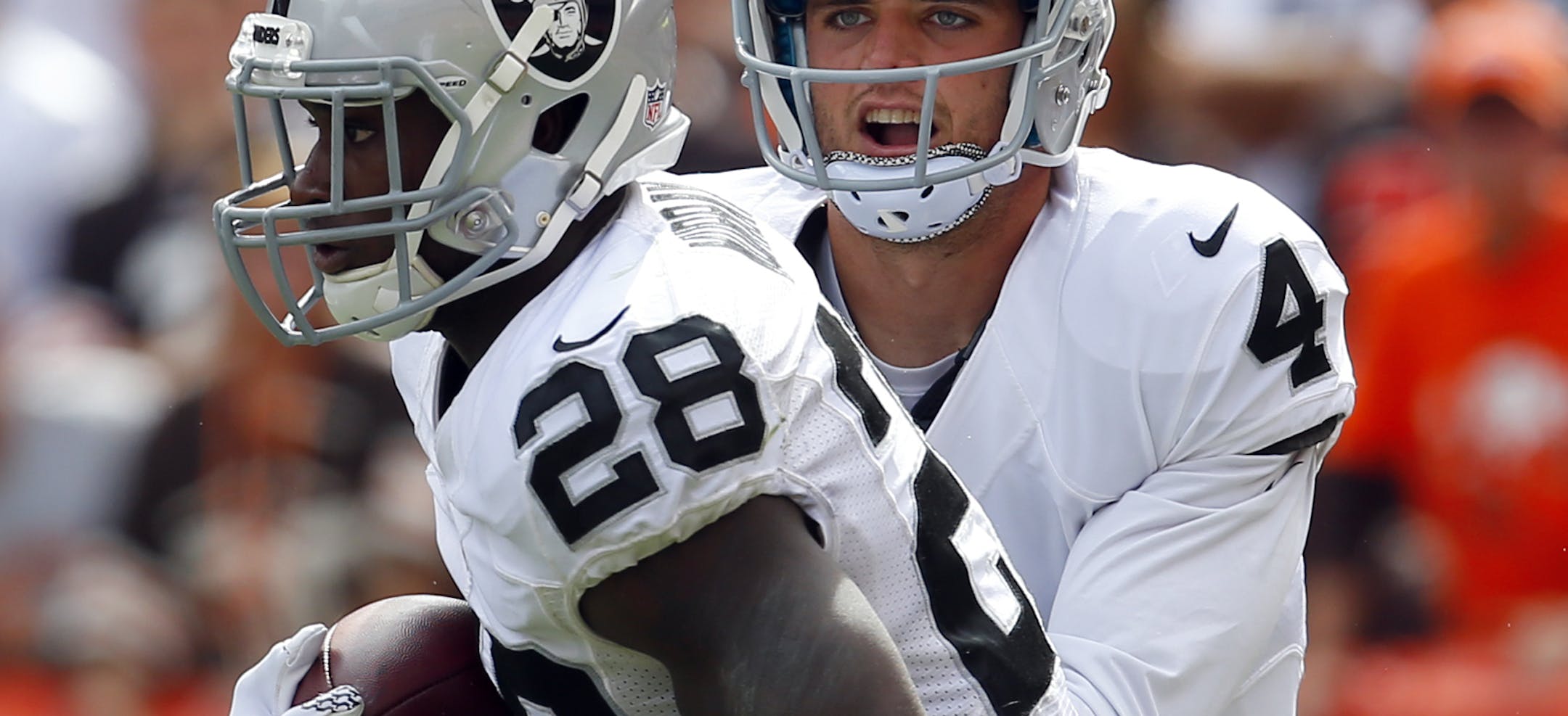 Oakland Raiders quarterback Derek Carr (4) hands the ball off to running back Latavius Murray (28) during an NFL football game in Cleveland, Sunday, Sept. 27, 2015. (Jeff Haynes/AP Images for Panini)