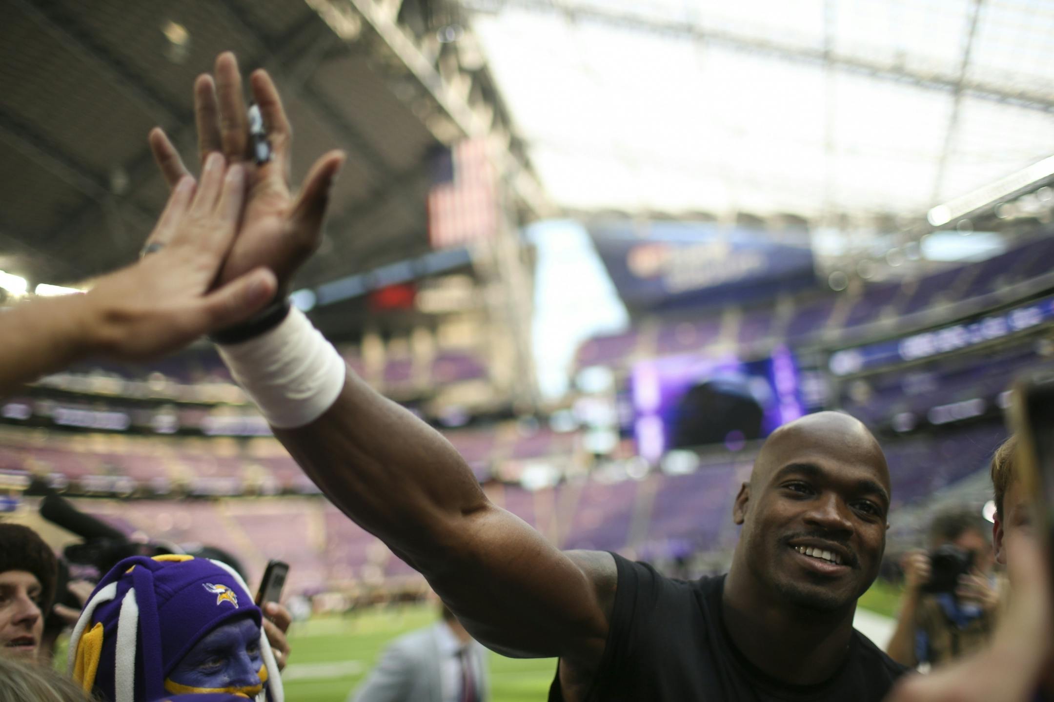 New Orleans Saints running back Adrian Peterson high fived a fan while posting for a photo for another fan waved on the sidelines during pregame warmups before Monday night's game.