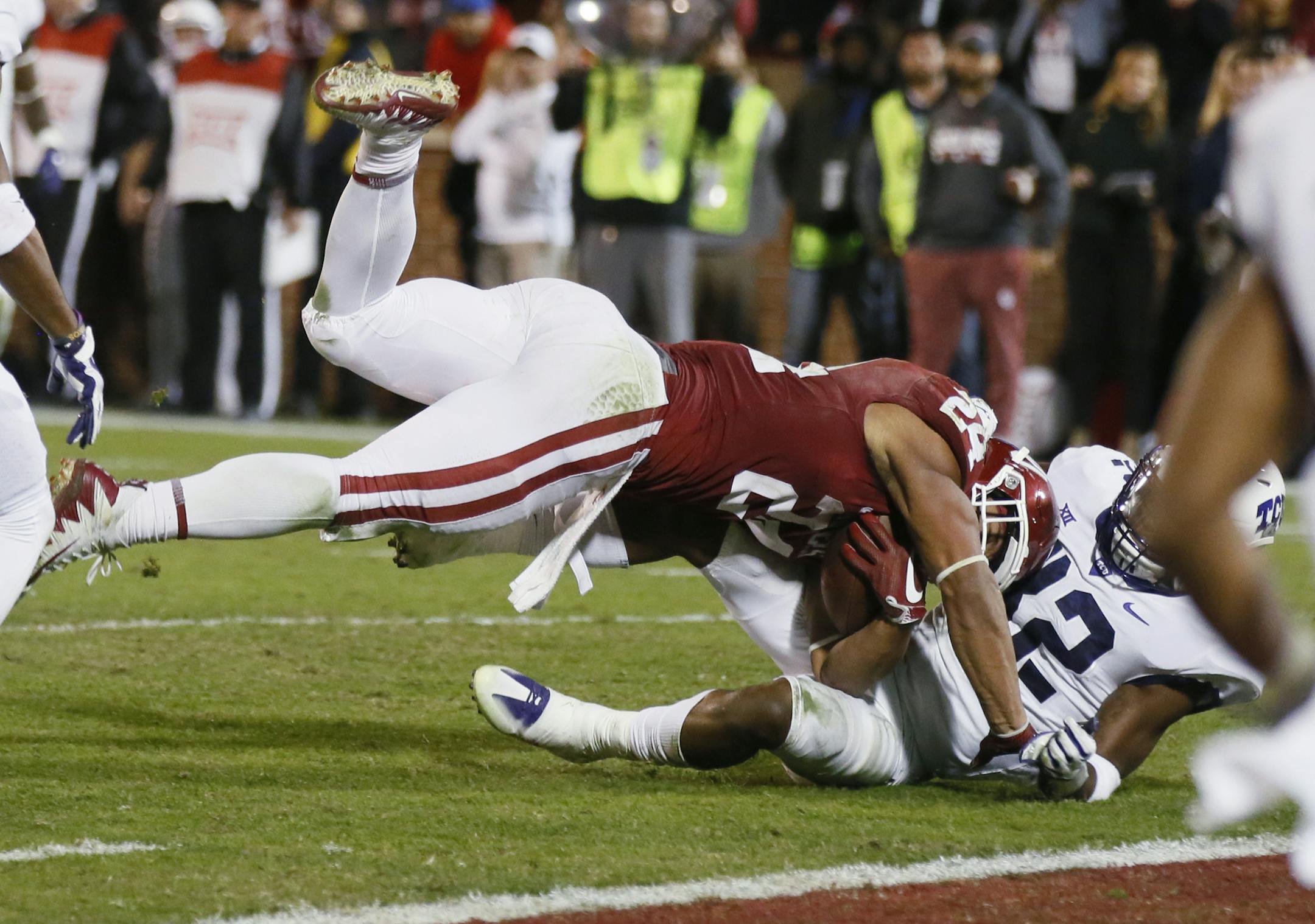Oklahoma running back Rodney Anderson, left, tumbles into the end zone with TCU linebacker Travin Howard, right, for a touchdown in the second quarter of an NCAA college football game in Norman, Okla., Saturday, Nov. 11, 2017. (AP Photo/Sue Ogrocki)