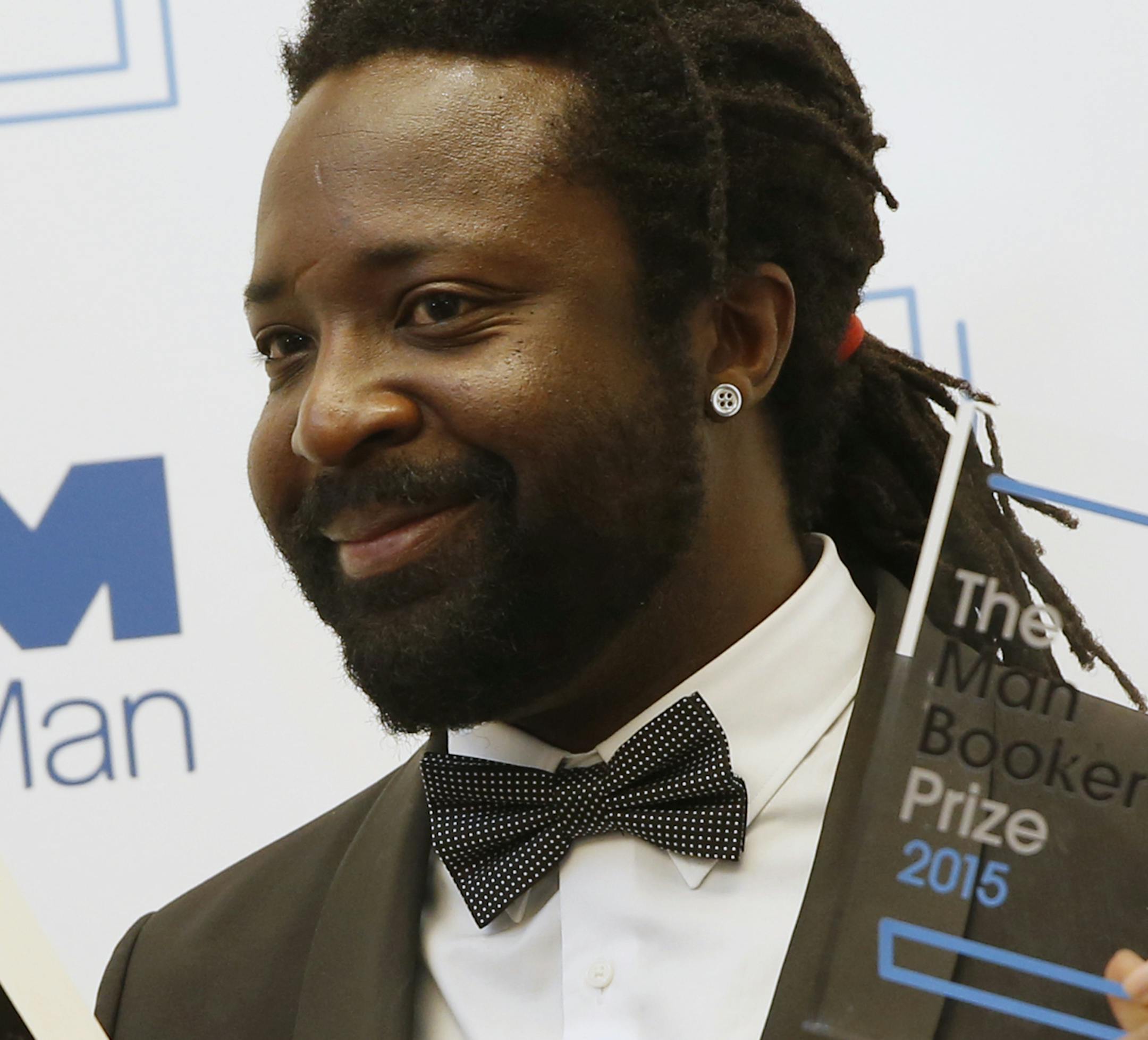 Jamaican author Marlon James holds his novel and the award after his book 'A Brief History of Seven Killings' was named as winner of the 2015 Booker Prize 2015 for Fiction, poses for photographers following the award ceremony at the Guildhall in London, Tuesday, Oct. 13, 2015. Marlon James became the first Jamaican winner of the prestigious Booker Prize for fiction Tuesday with a vivid, violent, exuberant and expletive-laden novel based on the 1976 attempted assassination of Bob Marley.(AP Photo