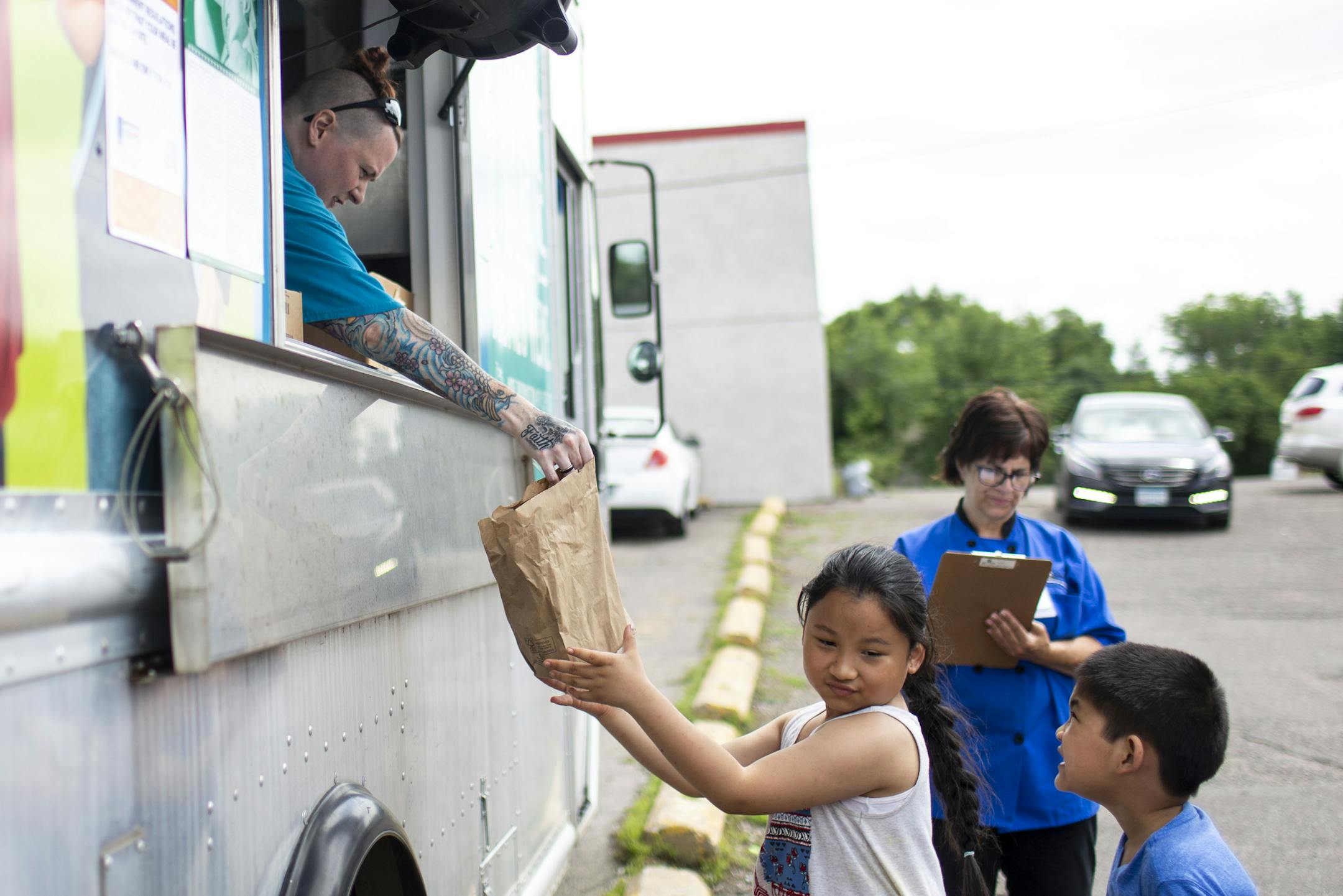 Erin George handed children a free lunch from the Summer Food Service Program truck at a St. Paul apartment complex in 2019.