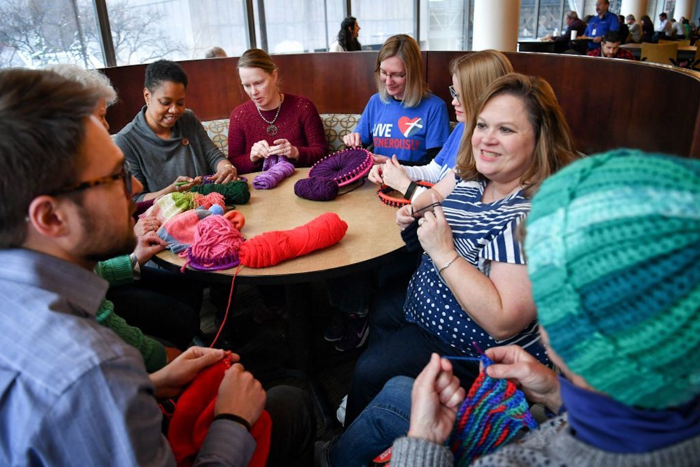 Nine members of Get Stitchy gathered at Thrivent where they knitted or crocheted hats and mittens in an effort to donate 5200 items for their Super Bowl charity event.