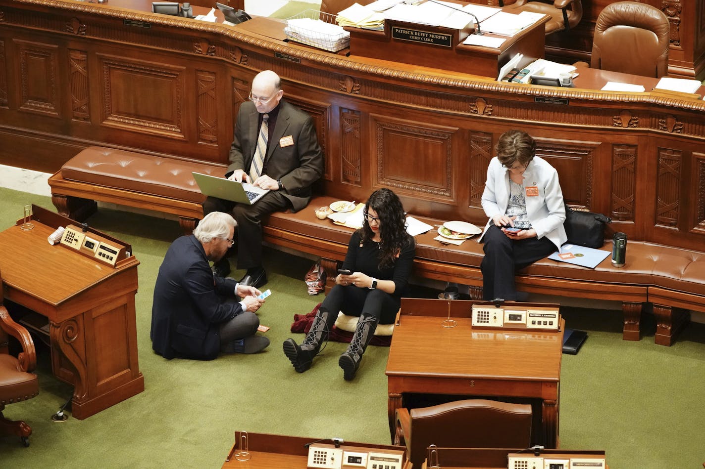 State Rep. Erin Maye Quade, of Apple Valley, second from right, holds a 24-hour sit-in on the Minnesota House floor for stronger gun laws, Tuesday, April 24, 2018, in St. Paul, Minn., joined by fellow Democratic-Farmer-Labor Party Reps. Raymond Dehn, Minneapolis, seated on floor; Peter Fischer, Maplewood, and JoAnn Ward, Woodbury. (Glen Stubbe/Star Tribune via AP)