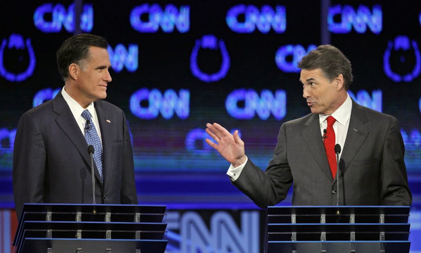 Republican presidential candidates Texas Gov. Rick Perry, right, speaks to former Massachusetts Gov. Mitt Romney during a Republican presidential debate Tuesday, Oct. 18, 2011, in Las Vegas.