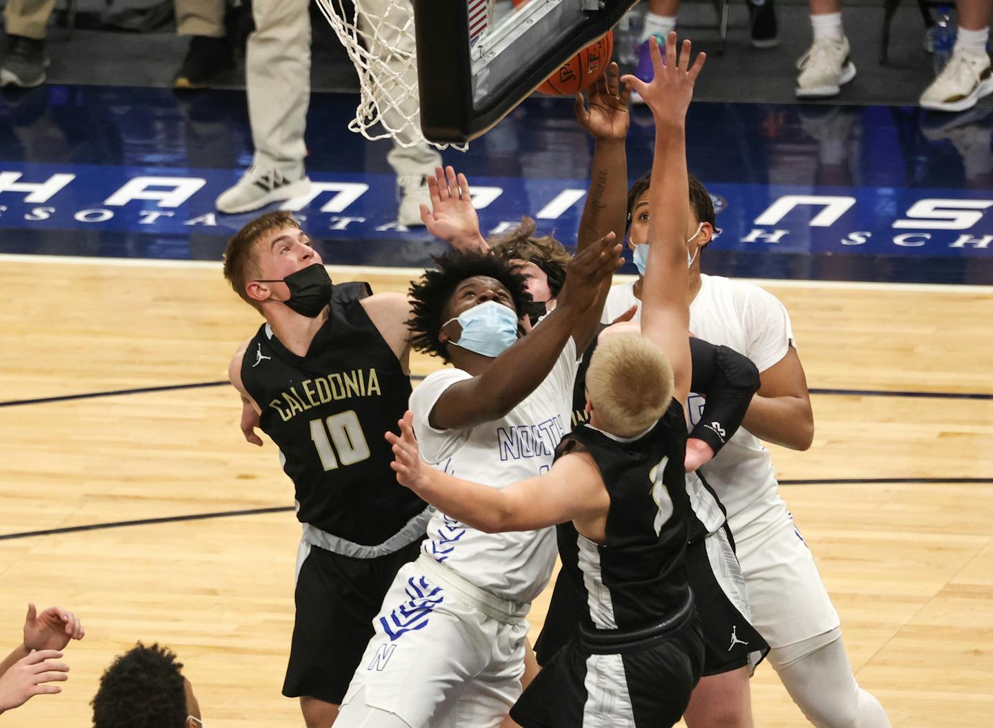 Caledonia's Jackson Koepke (10) and Austin Klug (3) defend Minneapolis North's Mario Sanders (1) under the basket in the Class 2A semifinal Wednesday at Target Center. Koepke led all scoring in the first half with 11 points. Photo by Cheryl A. Myers, SportsEngine