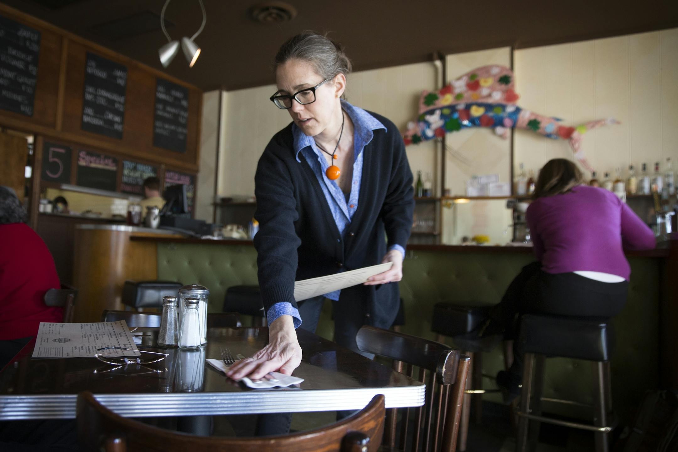Modern Cafe co-owner Patty Grell sets a table at her restaurant in Minneapolis on Tuesday, March 10, 2015.