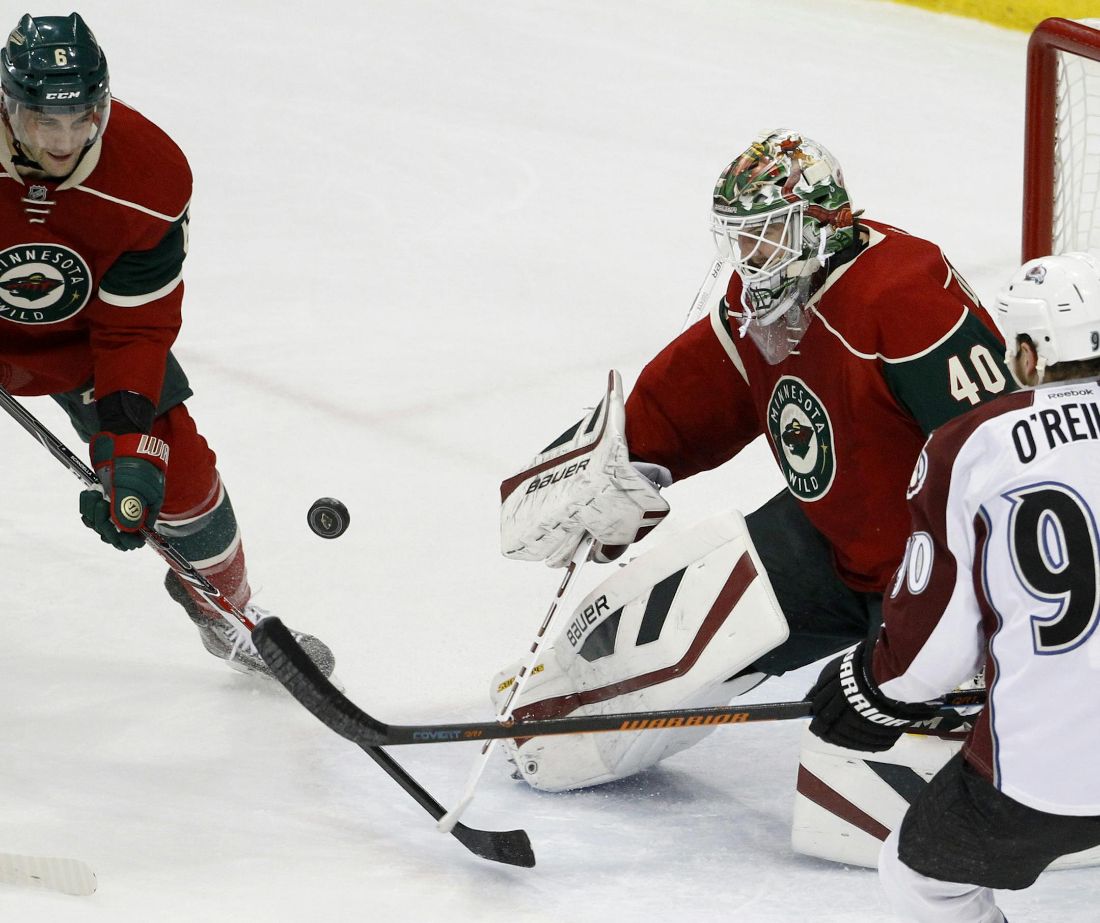 Minnesota Wild goalie Devan Dubnyk (40) deflects a shot in front of Colorado Avalanche center Ryan O'Reilly (90) and Wild defenseman Marco Scandella (6) during the first period of an NHL hockey game in St. Paul, Minn., Saturday, Feb. 7, 2015. (AP Photo/Ann Heisenfelt)