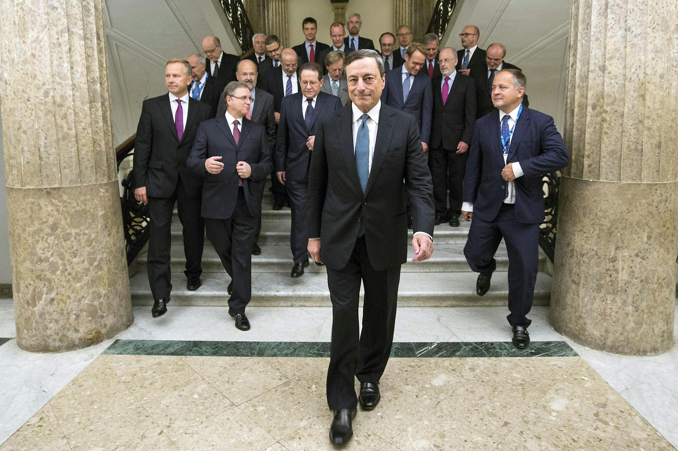 President of European Central Bank Mario Draghi walks in front of the ECB governing council prior to their meeting in Naples, Italy, Thursday, Oct. 2, 2014. European Central Bank head Mario Draghi is expected Thursday to underline the bank's willingness to deploy more economic stimulus measures, a stance that could send the euro skidding even lower. And a drop in the currency which helps eurozone exporters and could nudge up worryingly low inflation might be the most effective stimulus to come o