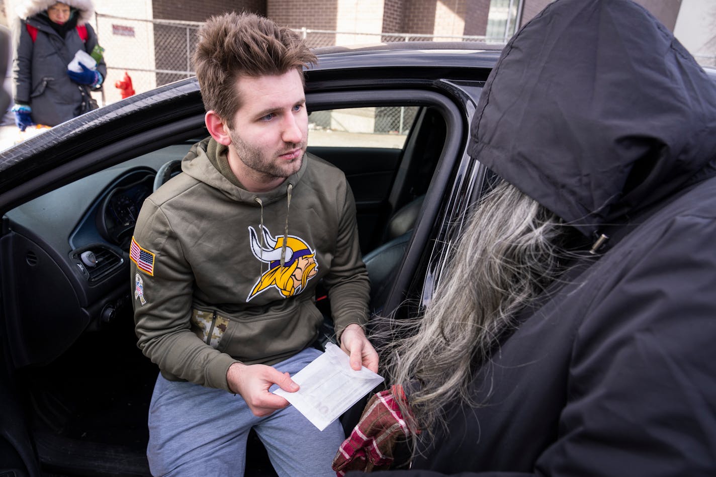 TikTok creator Josh Liljenquist gives a large sum of cash to Shannon Russell while passing out egg rolls to homeless people outside Dorothy Day Center in St. Paul, Minn. Thursday, Jan. 11, 2024. ] LEILA NAVIDI • leila.navidi@startribune.com