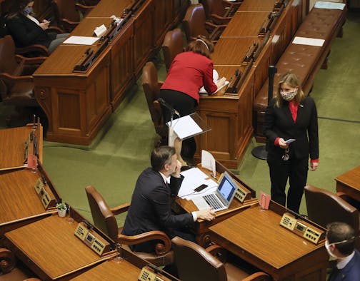 Minnesota House Speaker Melissa Hortman, standing, right, confers with Majority Leader Ryan Winkler, left, as the House met to take up several bills, including the insulin affordability bill, Tuesday, April 14, 2020 in St. Paul, Minn. (AP Photo/Jim Mone)