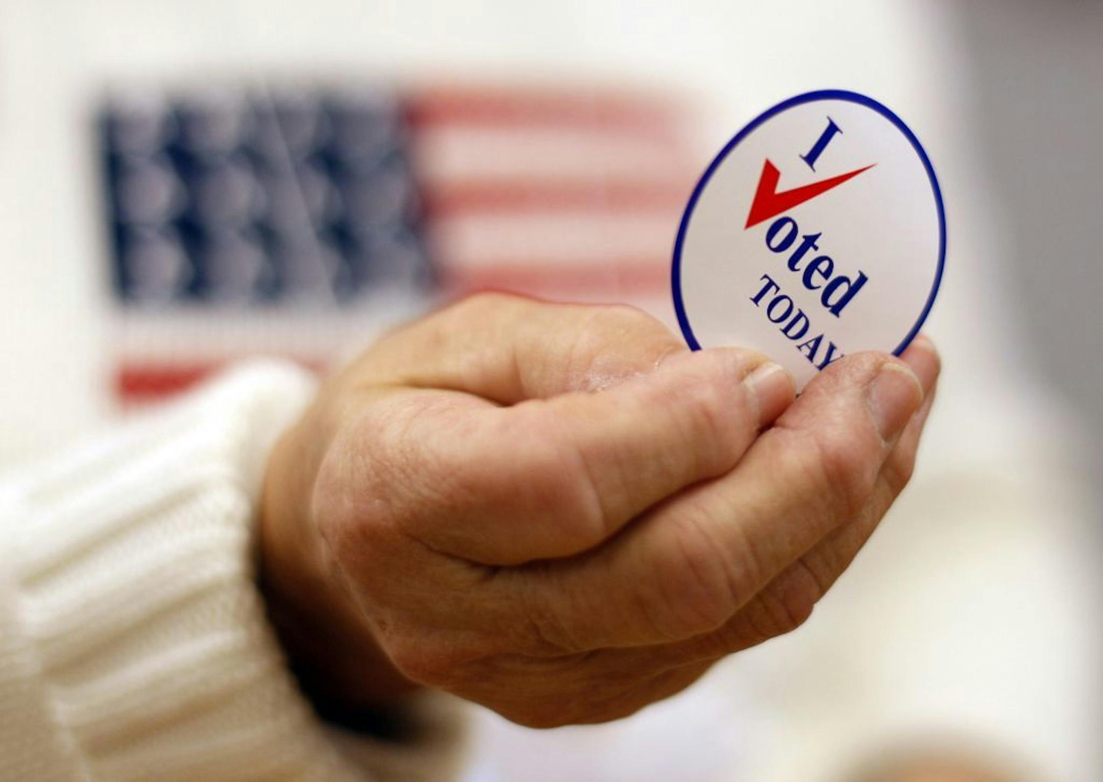 A sticker is handed to a voter on Election Day, Tuesday, Nov. 2, 2010, in Waterville, Maine.
