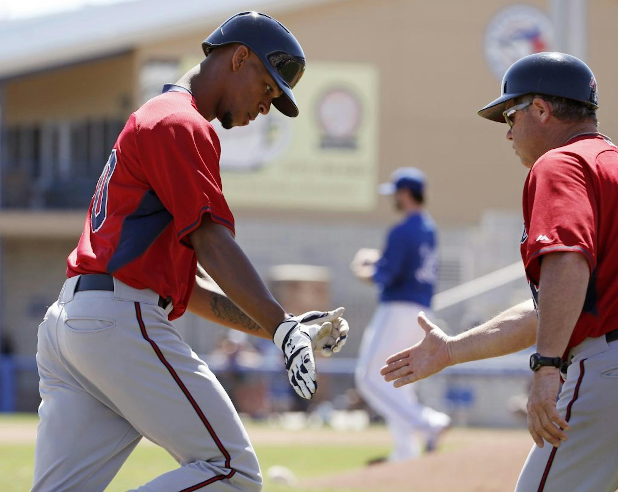 Minnesota Twins third base coach Joe Vavra, right, congratulates Byron Buxton (70) after Buxton hit a solo home run off Toronto Blue Jays starting pitcher Drew Hutchison, center, during a spring training baseball game Saturday, March 8, 2014, in Dunedin, Fla.