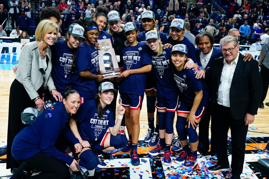 UConn players hold up the East Region championship trophy after defeating NC State in double overtime.