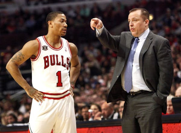 In this photo taken Saturday, March 12, 2011, in Chicago, Tom Thibodeau, right, directs his team as guard Derrick Rose listens