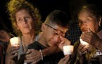 Mona Rodriguez, Jayanthony Hernandez, 12 and Juanita Rodriguez, from left, participate in a candlelight vigil held for the victims of a fatal shooting