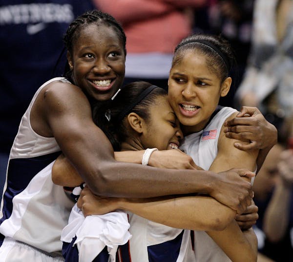 Connecticut’s Tina Charles, left, and Maya Moore, right, hug Renee Montgomery with moments left in Connecticut’s 76-54 win over Louisville in the 