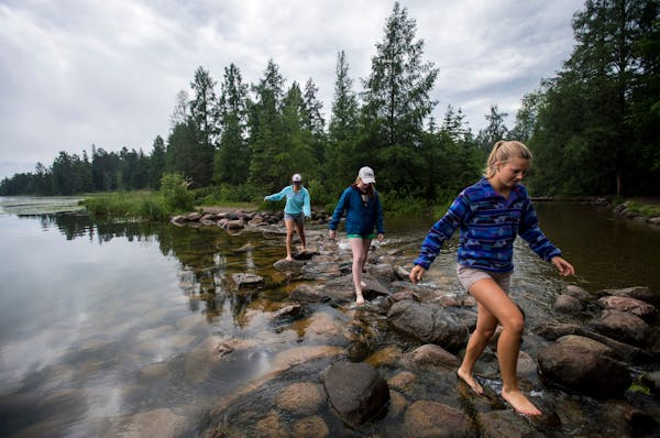 Emma Daniels, right, Abby MacFarlane and Marie Preston, back, walked across the rocks at the headwaters of the Mississippi at Lake Itasca in mid June.
