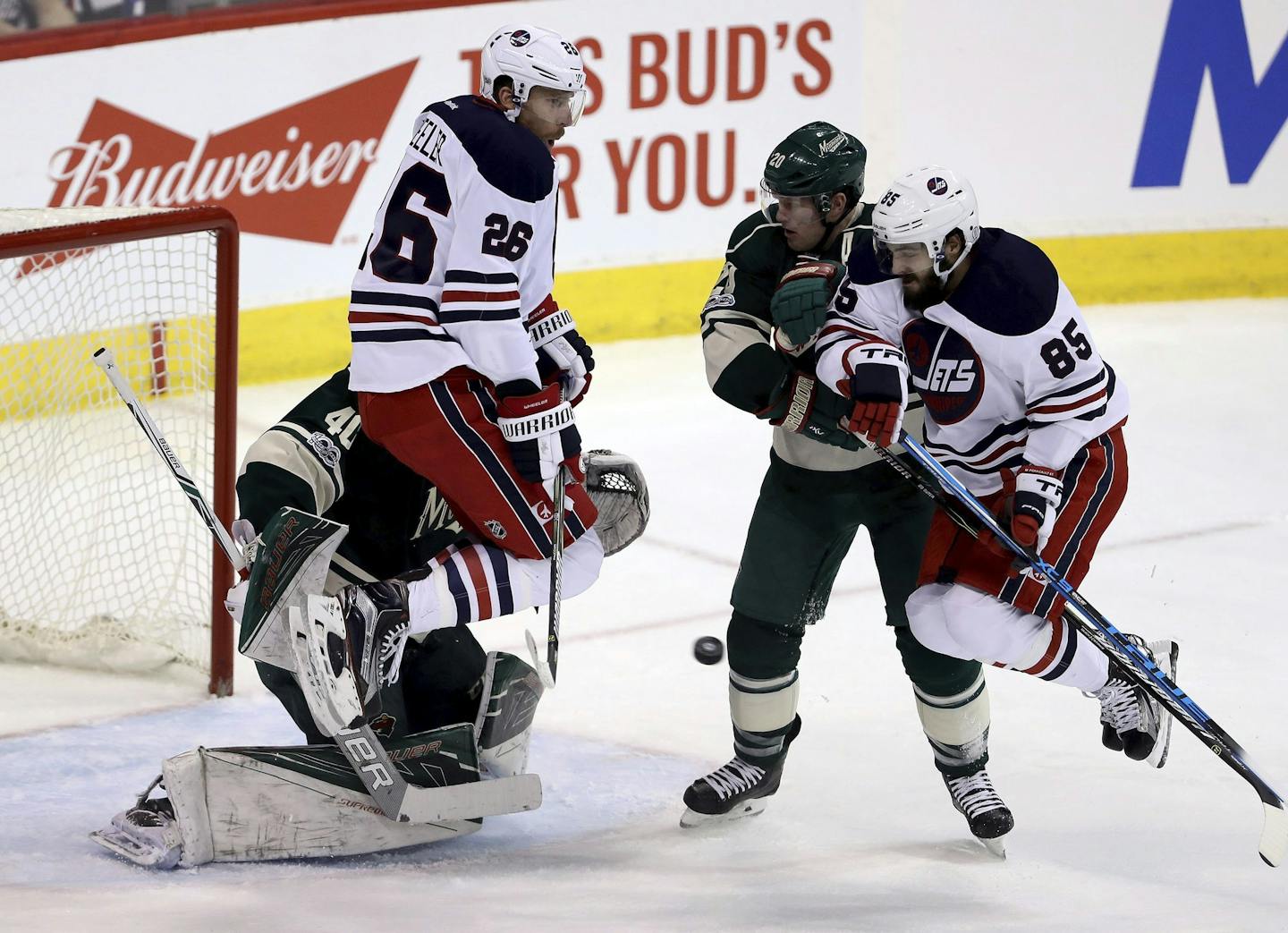 Winnipeg Jets' Blake Wheeler (26) and Mathieu Perreault (85) both jump over a shot while screening Minnesota Wild goaltender Devan Dubnyk (40) with Wild's Ryan Suter (20) in front of the net during the first period of an NHL hockey game in Winnipeg, Manitoba, Sunday, March 19, 2017. (Trevor Hagan/The Canadian Press via AP)