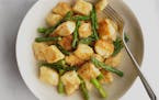 A bowl of cheesy dumplings with asparagus in a lemon-brown butter sauce.