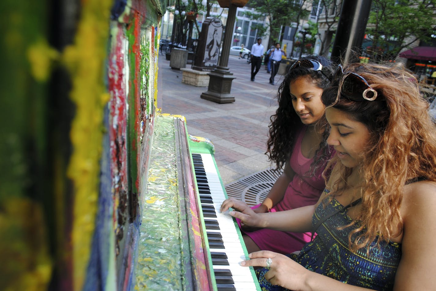 Cousins Genevieve D'Cruz of Chapel Hill, N.C., left, and Grace D'Mello of Minneapolis tickle the ivories of the colorful piano outside Park Square Theatre in downtown St. Paul.