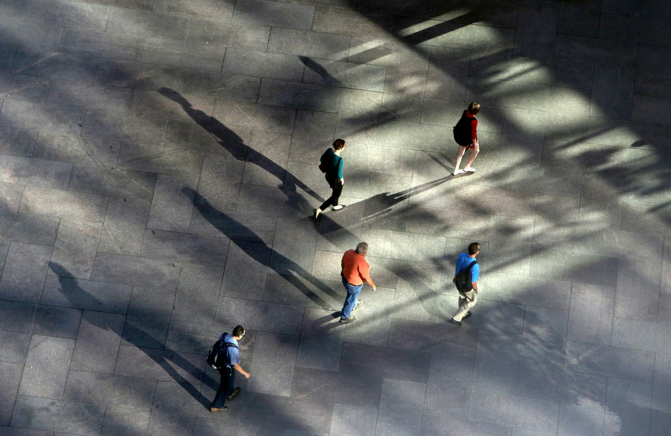 Pedestrians cast long shadows while walking on U.S. Bank Plaza in Minneapolis.